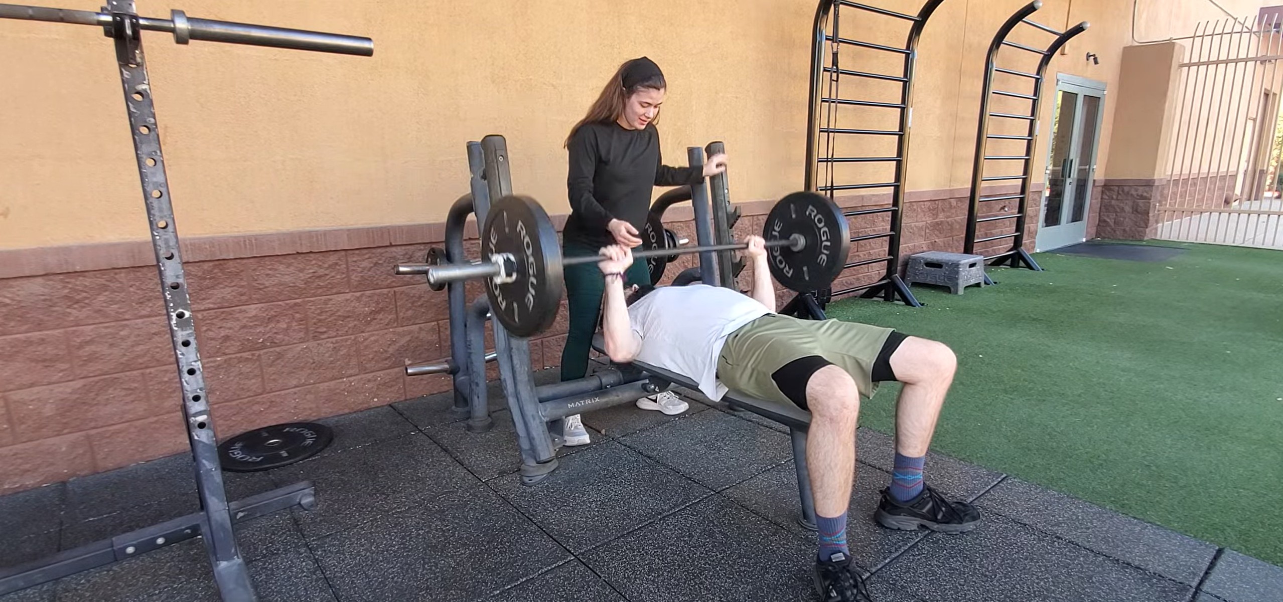 Trainer helping client on bench press